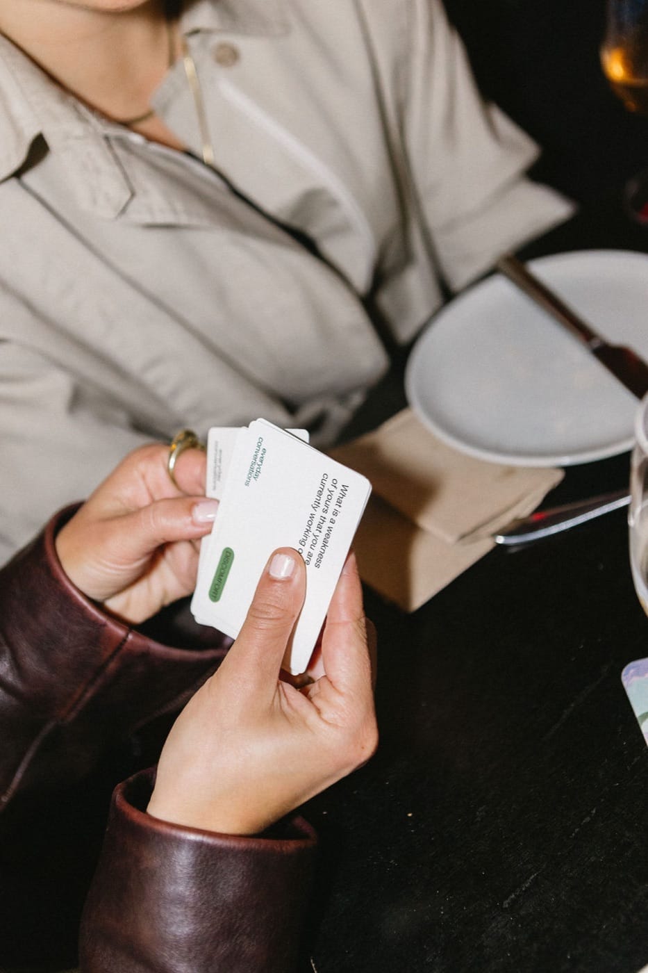 Person holding Everyday Conversations cards at a table